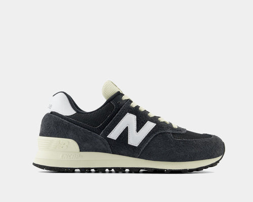 New Balance 574 sneakers in black suede and mesh with white logo and cream midsole, side view.