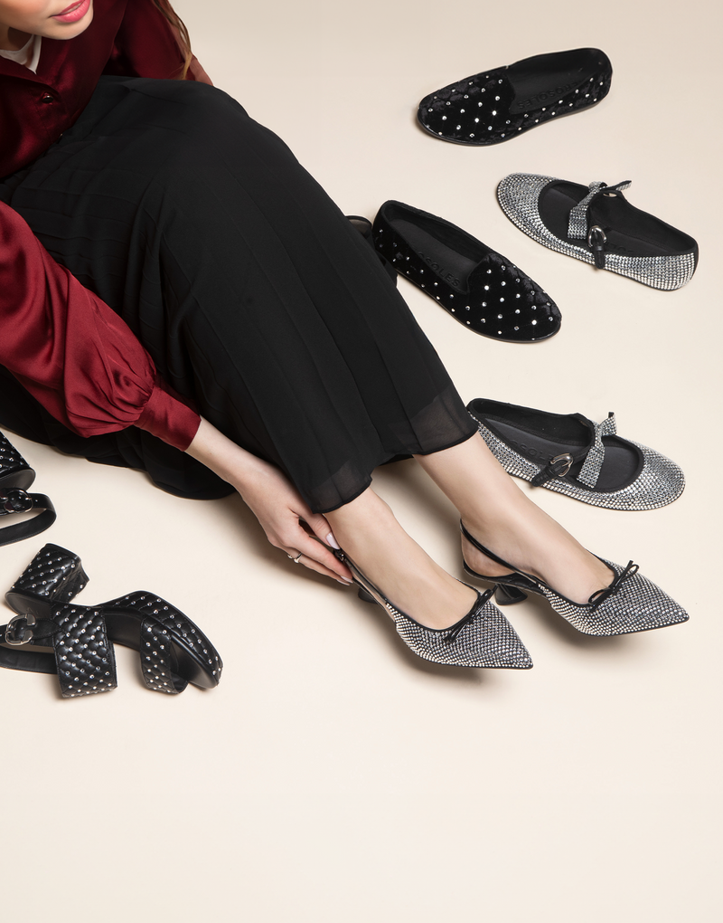 Woman sitting on the floor, surounded by shoes and trying on Comfortable Women's Platform Sandal in Black Quilted Faux Leather With Crystals
