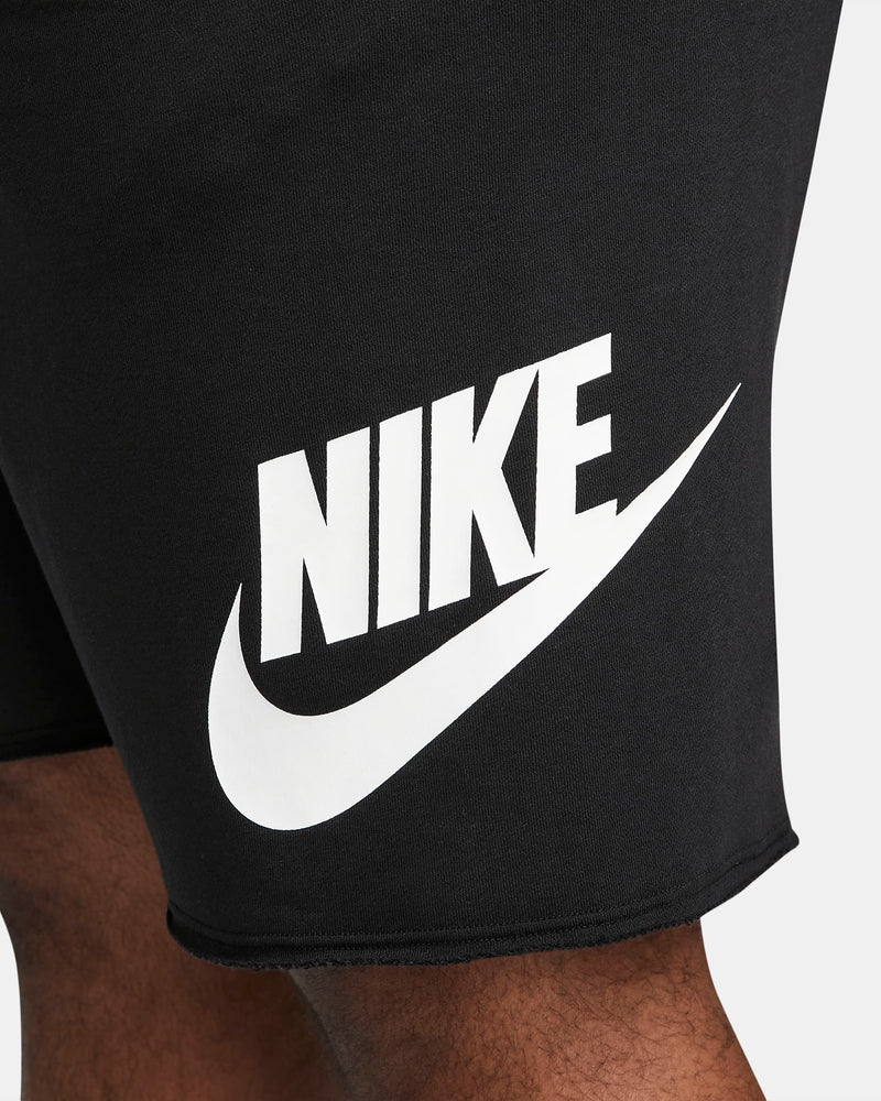 Nike French Terry Alumni Shorts in black featuring large white Nike logo and raw edge hem, side close-up detail view.