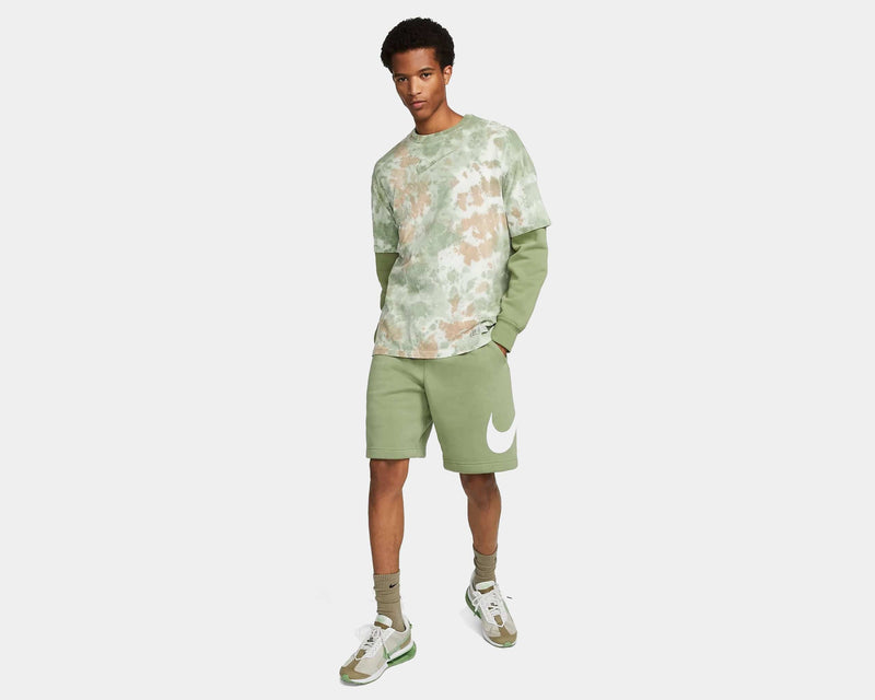 Nike Sportswear Club Shorts in light green with large white Nike logo on left leg, worn by model standing.